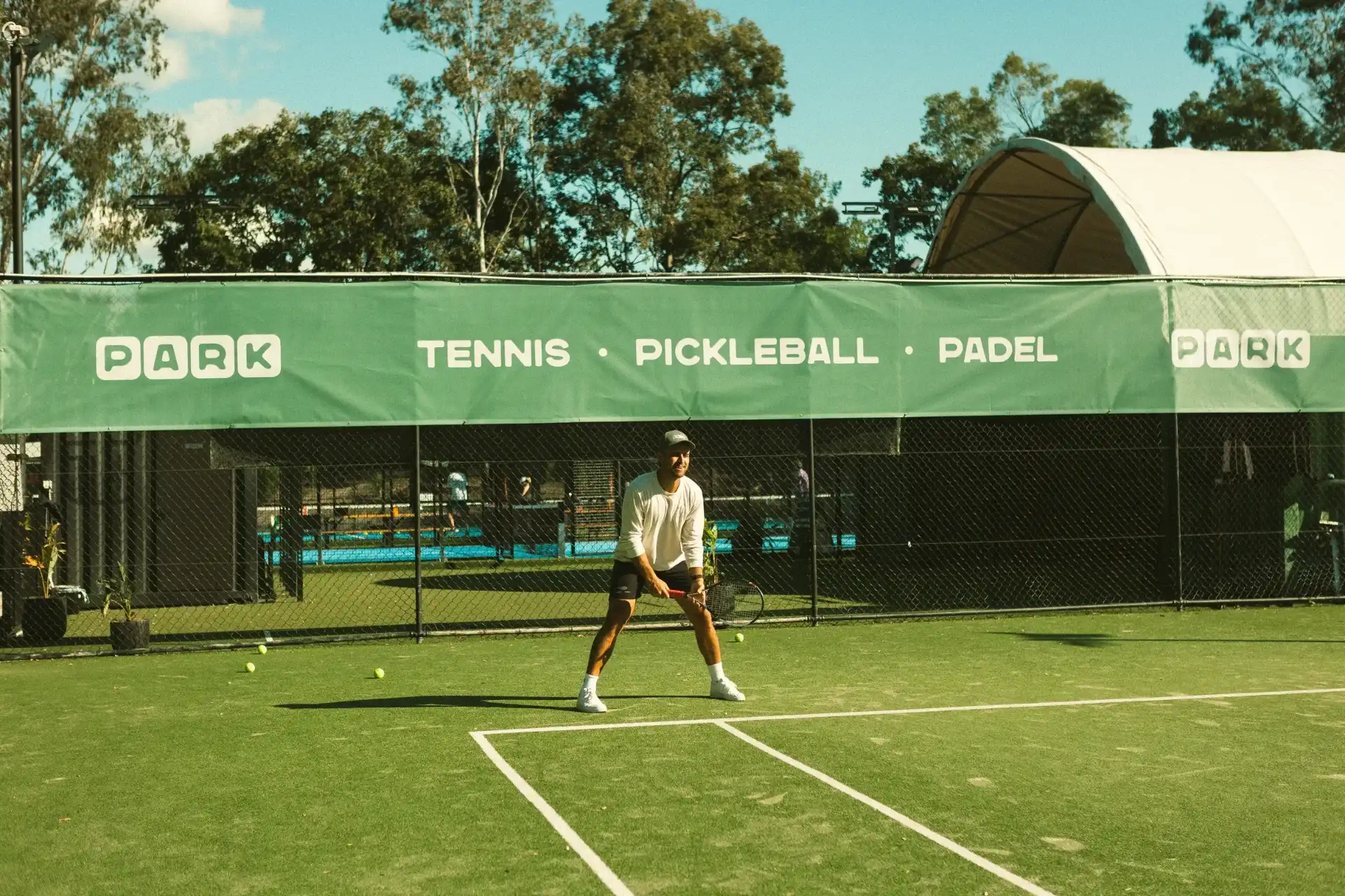 Grass tennis court at PARK The Gap, with the padel and pickleball courts behind.